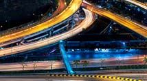 Freeway with zooming cars and bright lights supported by infrastructure