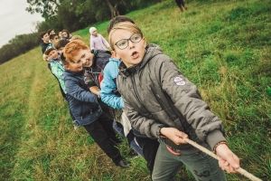 tween girls pulling on a rope in a tug of war game outdoors