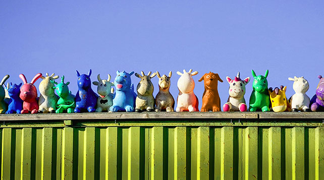 Colorful toy animals lined up and perched atop a green metal shipping container