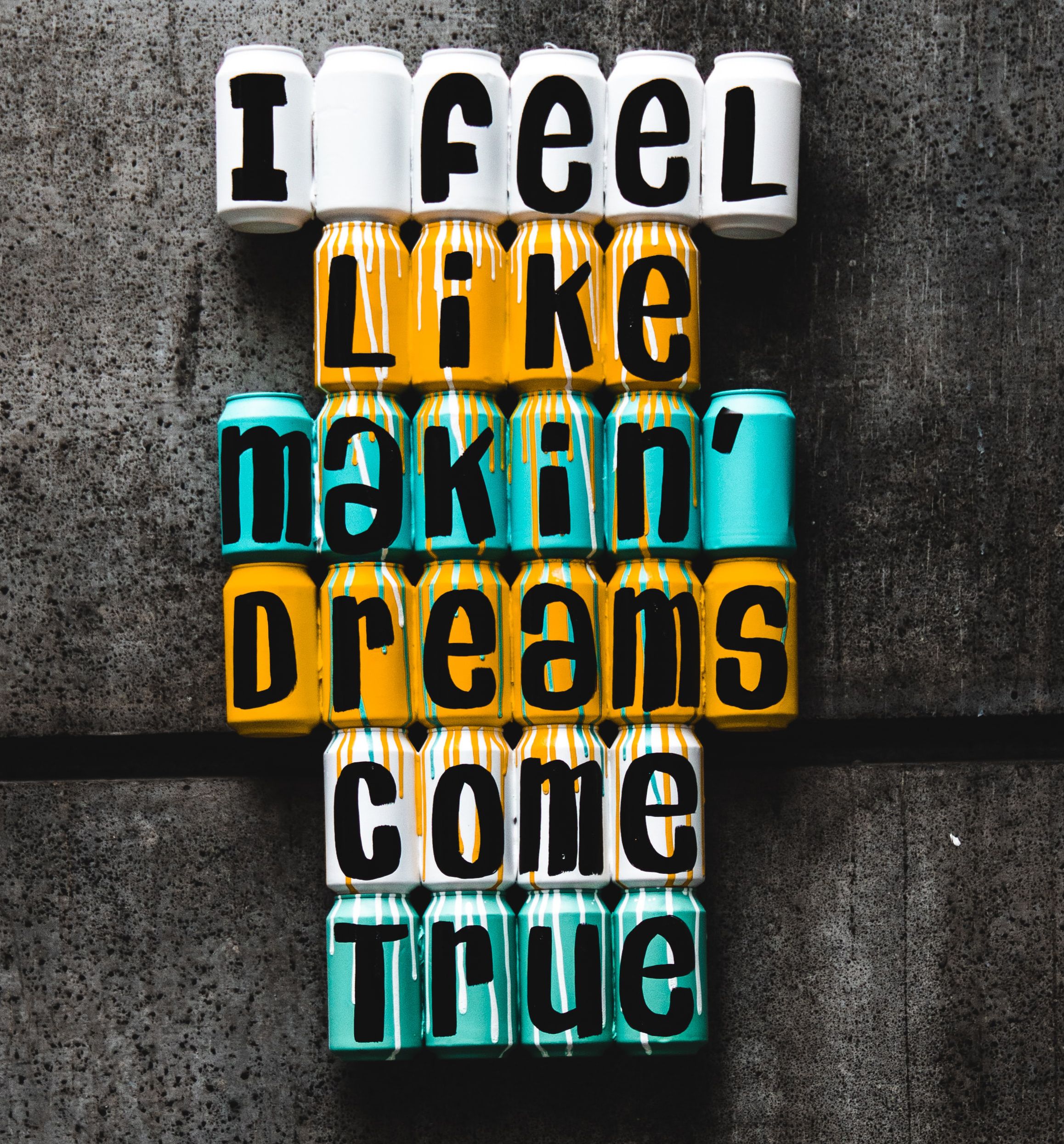 Sprat painted cans with letters spelling out "i feel like makin' dreams come true" in green, white and orange