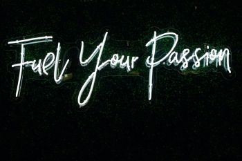 Neon sign with white cursive letters that reads: Fuel Your Passion